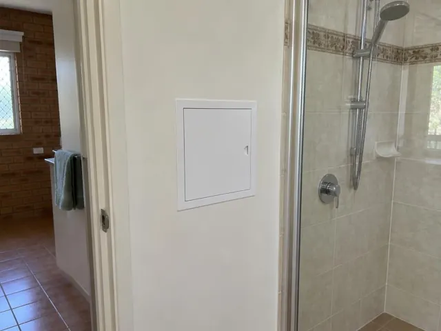 Neat access panel in a tiled bathroom wall beside a shower in Bexley North